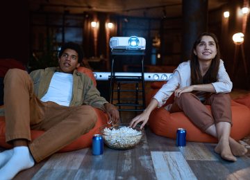Couple eating popcorn. Young man and woman enjoy watching exciting movie. Home cinema